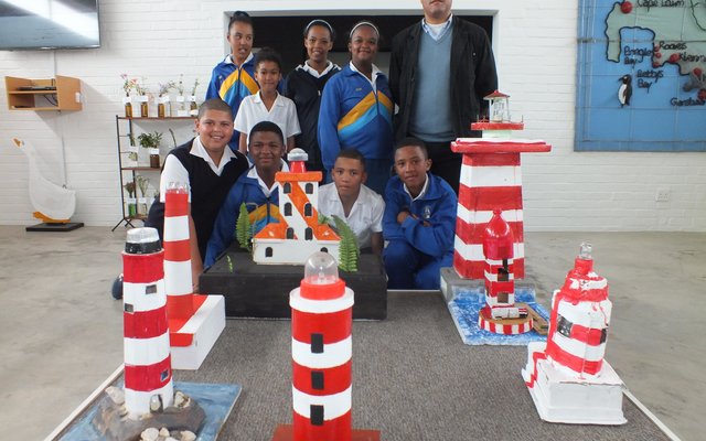 Hier is die groep leerders van Gansbaai Primêr by hulle vuurtorings wat hulle gebou het, met Adjunkhoof Niel Pedro agter regs 